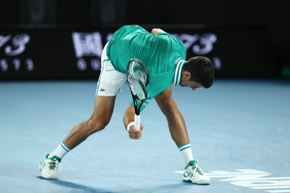 Novak Djokovic smashes his racquet on the court.