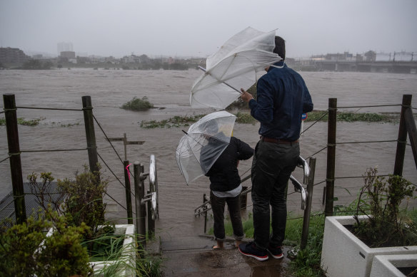 People look at the flooded Tama River during Typhoon Hagibis on October 12