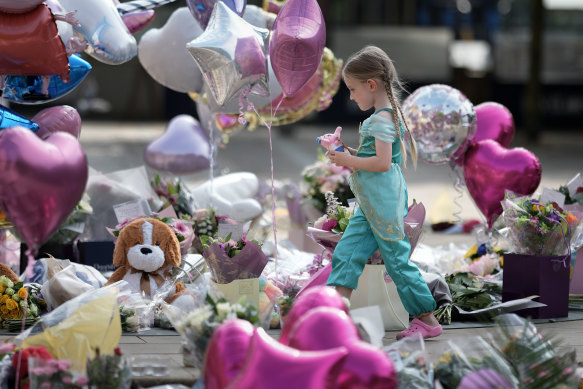 A young girl pays her respects among the thousands of flowers and tributes left for the victims of the Southport attack.