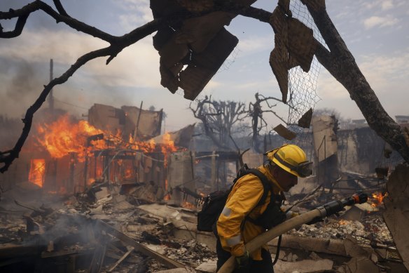A firefighter battles the blaze around a burned structure in the Pacific Palisades neighbourhood of Los Angeles in January.