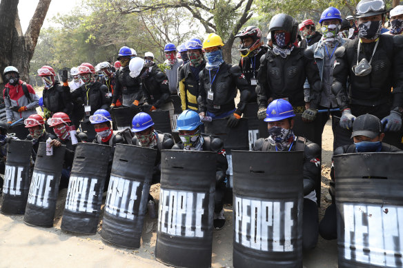 Anti-coup protesters wearing helmets and face masks gather during a protest in Mandalay, Myanmar, Saturday, March 6, 2021. 