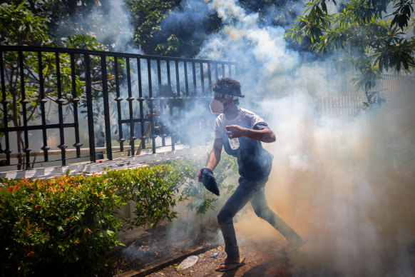 A protester runs for cover after soldiers fire tear gas during street violence in Colombo.