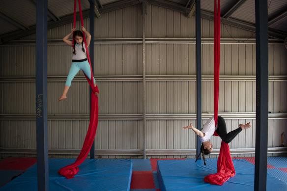 Eleni, 14, and Amity Khouchaba, 9, practice doing aerial acrobatics on silks in their back shed at their home in Mulgoa during lockdown.