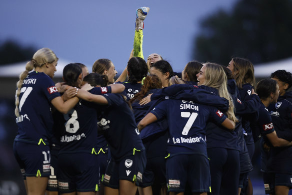 Melbourne Victory goalkeeper Casey Dumont raises her fist celebrate with teammates. 