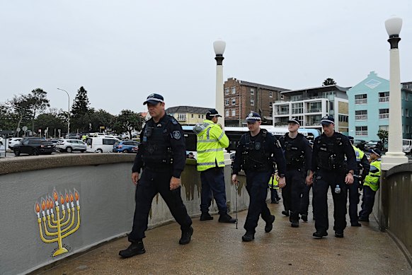NSW Police walk toward Bondi Beach in February, three months after gunmen opened fire into a crowd of Jewish families from the footbridge.