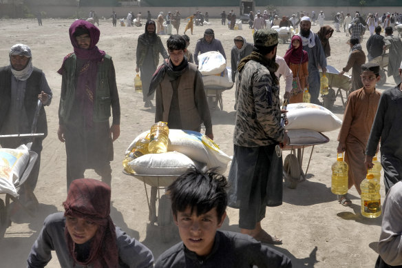 A Taliban fighter stands guard as people receive Chinese food rations, Kabul. 