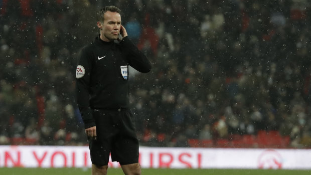Referee Paul Tierney gets advice on the radio from the VAR system during the English FA Cup fifth round replay between Tottenham Hotspur and Rochdale at Wembley.