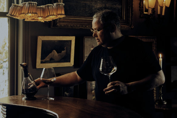 Jason Jones in Gigi’s bar, surrounded by oil paintings he has collected on his travels.
