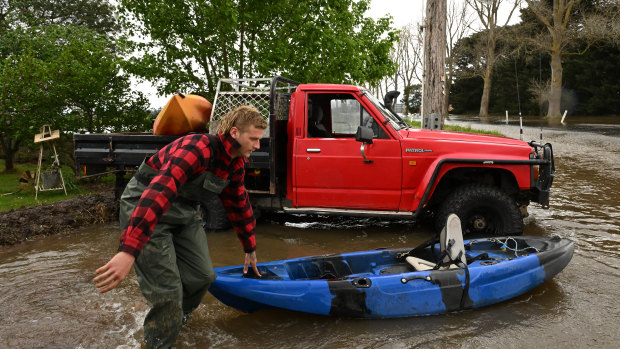 Riley Davis pushing a kayak through flood water in Tinamba in eastern Victoria.