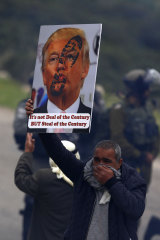 A Palestinian holds up a sign rejecting US President Donald Trump's "peace plan" during protests in the Jordan Valley in February.