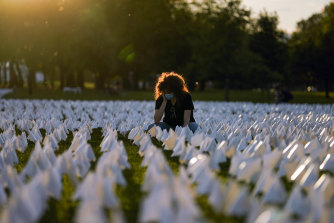 Zoe Nassimoff, of Argentina, looks at white flags that are part of artist Suzanne Brennan Firstenberg’s temporary art installation, “In America: Remember,” in remembrance of Americans who have died of COVID-19, on the National Mall in Washington, Friday, Sept. 17, 2021.