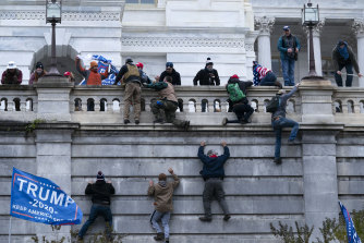Supporters of President Donald Trump climb the west wall of the  Capitol building.