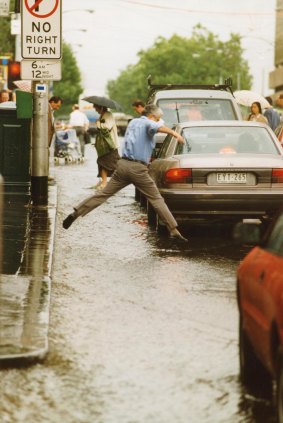 A valiant attempt to avoid wet feet, Flinders Street.