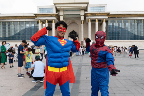 Ulanbaataar'daki Hükümet Sarayı'nın önünde çocuklar süper kahraman kostümleri giyiyor.