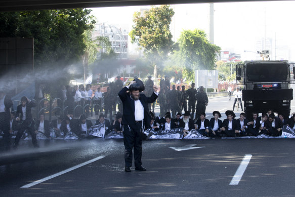Police officers use a water cannon as ultra-Orthodox Jewish men block a main highway during a protest against drafting into the Israeli army.