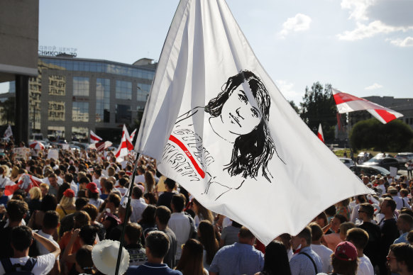 People at a rally in Minsk on Monday hold a flag with a portrait of presidential candidate Sviatlana Tsikhanovskaya.