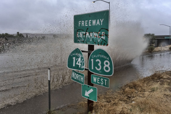 A vehicle engulfed in water drives through a flooded freeway in Palmdale, California, on Sunday.