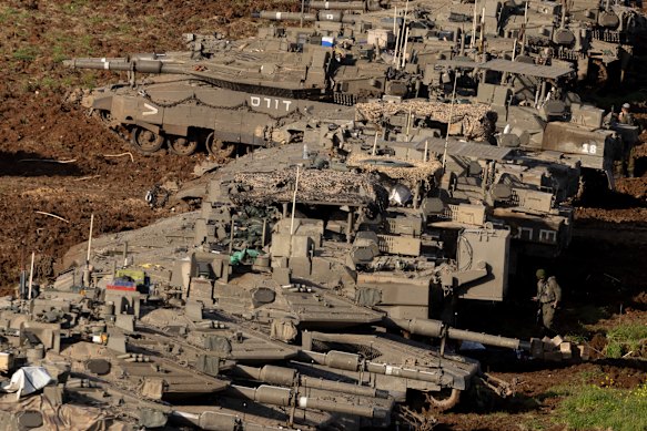 An Israeli soldier walks by tanks stand in position near their border with Lebanon.