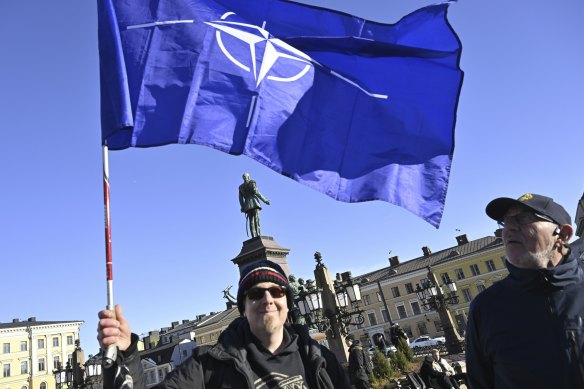 Two Finnish people with a NATO flag celebrate at the Senate Square in Helsinki, Finland.
