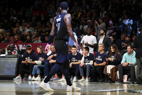 Kyrie Irving walks by fans in ‘Fight Antisemitism’ shirts during the Nets’ match against the Indiana Pacers.