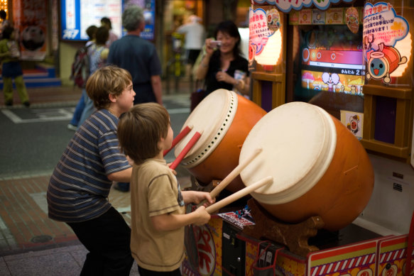 Children play a taiko drum video game in Shinjuku.