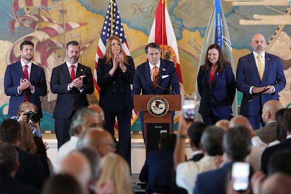 I membri del pubblico fanno una standing ovation mentre il procuratore generale ad interim Todd Blanche, al centro, parla a un evento in cui i procuratori federali hanno annunciato accuse contro l'ex presidente cubano Raul Castro.