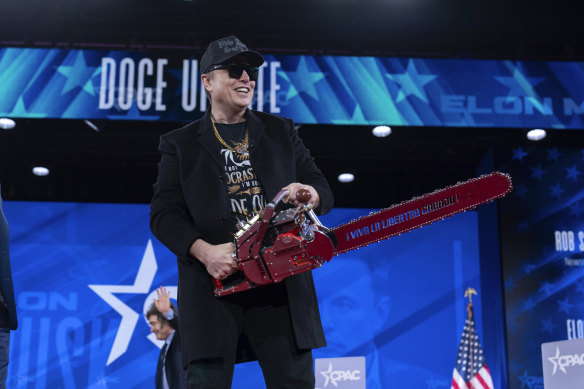 Elon Musk holds a chainsaw as he arrives to speak at the Conservative Political Action Conference.