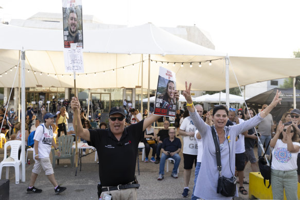 People celebrate in Tel Aviv as they hold photos of released hostages Noa Argamani and Almog Meir Jan.