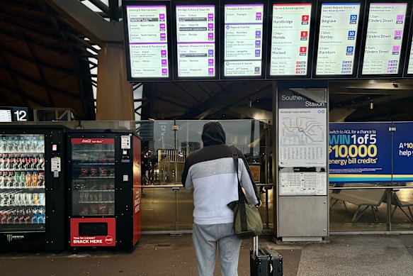 A commuter travelling to Traralgon looks at the delayed V/Line train services on the arrivals and departures information board at Southern Cross station.