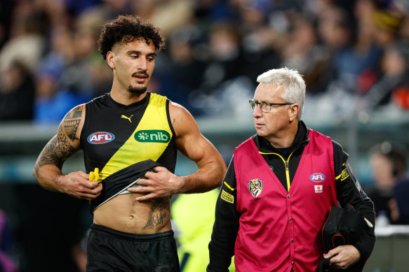 Mykelti Lefau of the Tigers heads to the change rooms with medical staff.