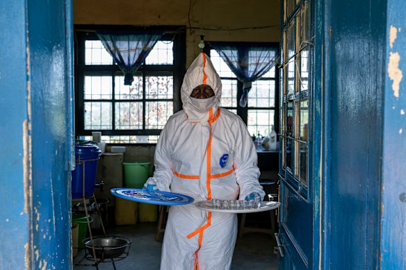 Ferdinand Kaso Lots’, a laboratory hygienist, takes lab supplies out into the sun for reuse at the general hospital.