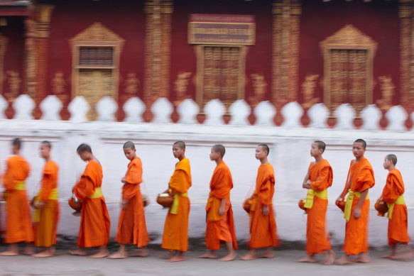 Monks collect alms in the UNESCO-Heritage listed town of Luang Prabang.