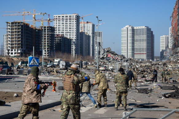 Ukrainian servicemen are seen at the explosion site as a result of a rocket strike into the shopping mall in Kyiv.
