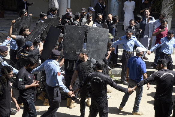 Private security personnel with bulletproof shields escort Imran Khan as he arrives to appear in a court in Islamabad on Tuesday. Officials from his party say he was subsequently arrested.