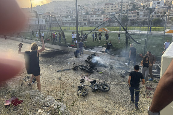 Residents rush to help injured children moments after a rocket attack hit a soccer field in the Druze town of Majdal Shams in the Israeli-occupied Golan Heights.