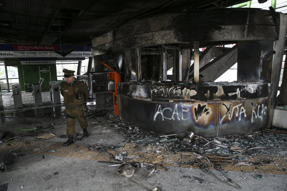 A police officer walks in a subway station that was torched during the protests in Santiago.