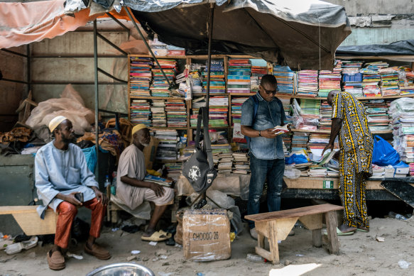 Germain-Arsene Kadi, a professor of literature who has written a dictionary of Nouchi, thumbs through a book at a street bookstore in the Adjame market where he still goes to discover new words, in Abidjan, Ivory Coast.