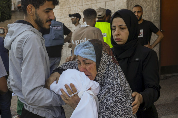 A Palestinian woman kisses the sheet-covered body of a child killed during an Israeli airstrike outside Al-Aqsa hospital in the Gaza Strip.