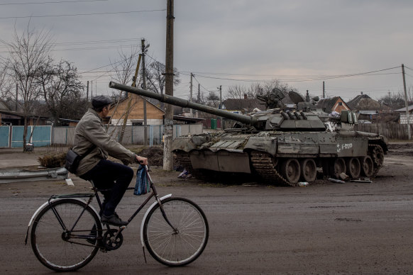 A man rides his bike past a destroyed Russian tank on March 30, 2022 in Trostyanets, Ukraine.