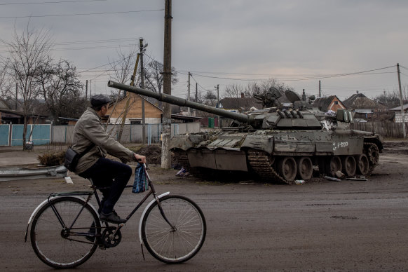 A man rides his bike past a destroyed Russian tank on March 30, 2022 in Trostyanets, Ukraine. 