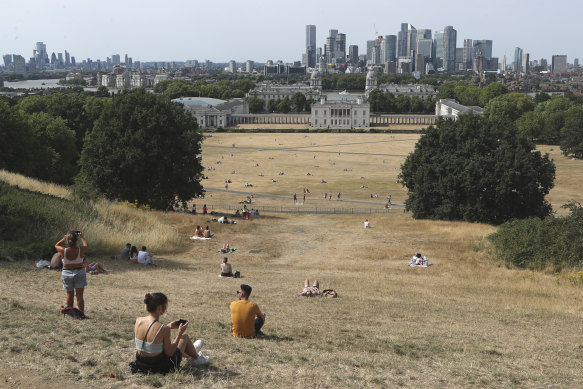 People sit on the sun-parched grass in Greenwich Park.