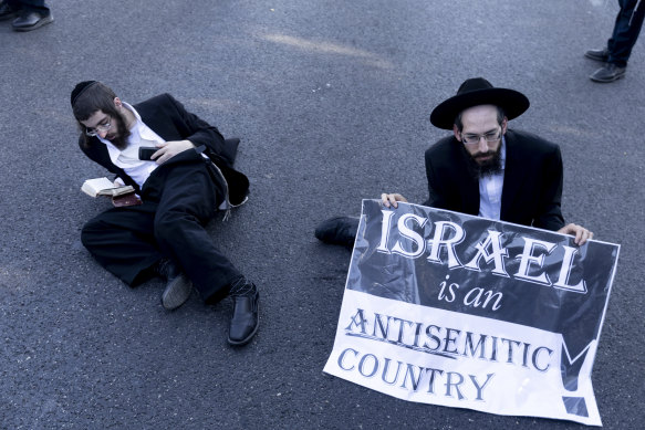 Ultra-Orthodox Jewish men hold signs and pray as they block a main highway during a protest against drafting into the Israeli army on June in Bnei Brak, Israel. 