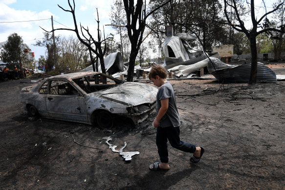 Eight year-old Jarrod McInnes walks next to the remains of a house that his family was about to buy and was destroyed by bushfires in Rappville, NSW in October.