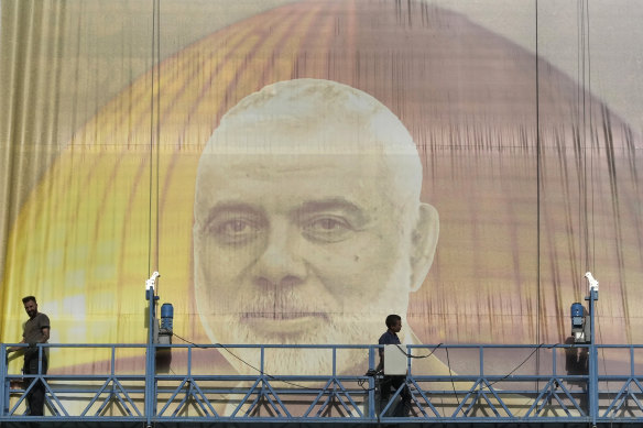 Iranian workers install a huge banner of Hamas leader Ismail Haniyeh in Tehran