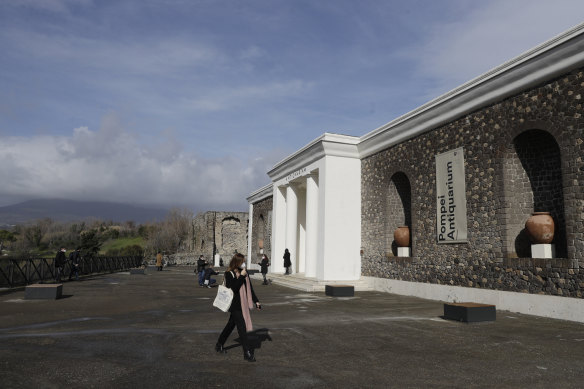 Clouds cover the Vesuvius volcano, background left, as journalists walk outside the museum Antiquarium, in Pompeii, Italy, on Monday.