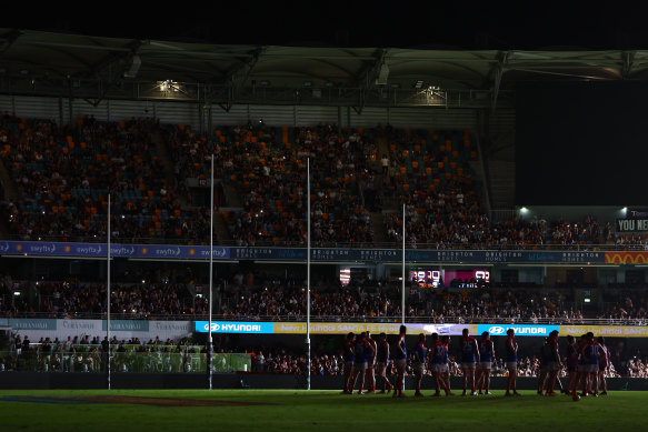 Lions and Demons players wait on field as power goes out during the round two match at the Gabba.