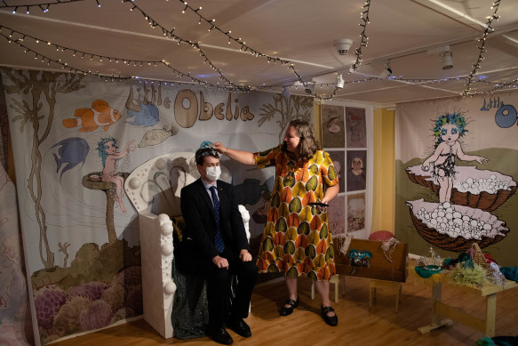 Curator, Selena Griffith places a crown on Christopher Wilks’s head  in the thinking room in the Little Obelia exhibition at Nutcote.