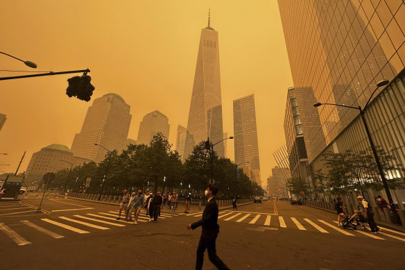 Pedestrians pass the One World Trade Center in New York amidst a smokey haze from wildfires in Canada.
