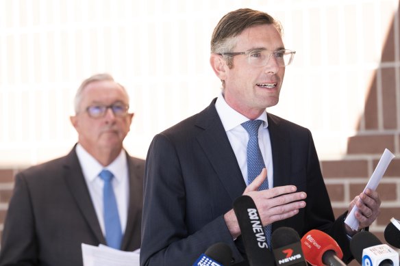 NSW Premier Dominic Perrottet, with Health Minister Brad Hazzard (behind) announces changes to COVID isolation rules on Wednesday.