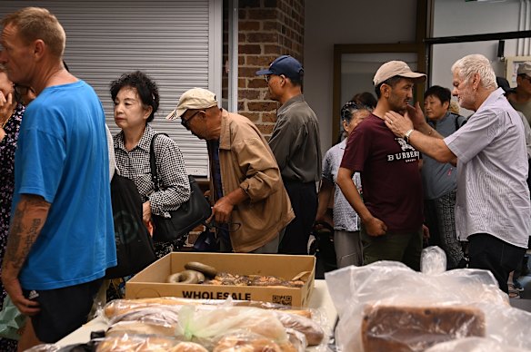 Paul Moussa (right) speaks to guests as the regular bread collection service opens.
